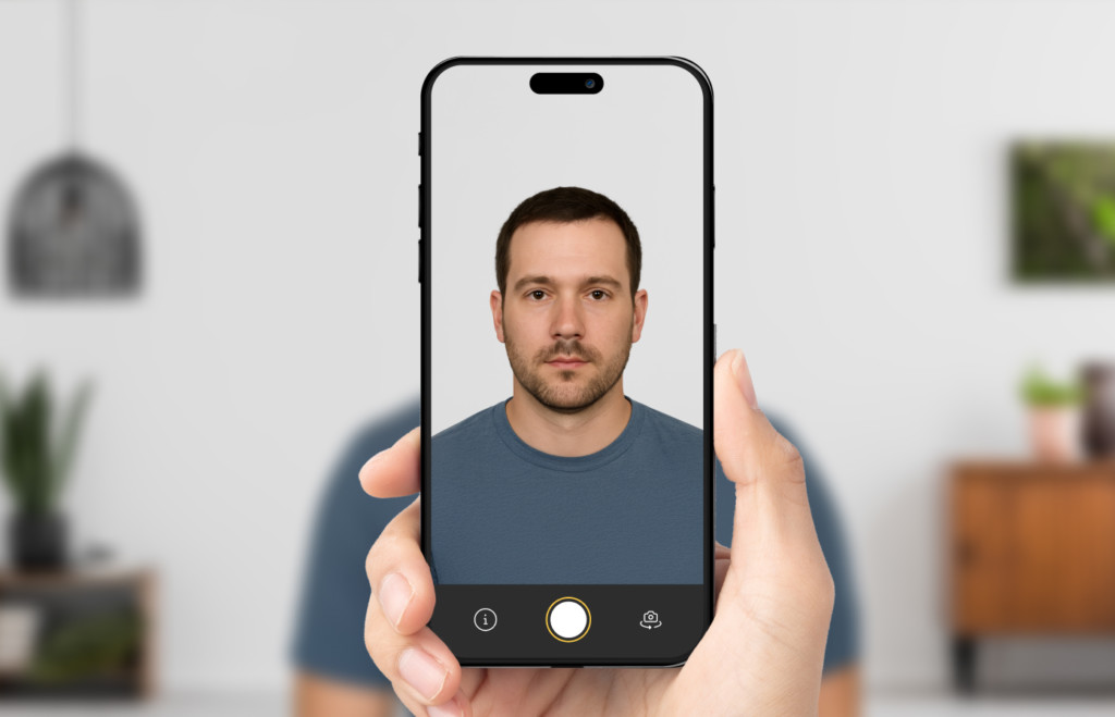 How To Take Passport Photo At Home Example of how to take passport photo at home, showing a person being photographed with a smartphone in front of a neutral background for proper alignment and lighting.