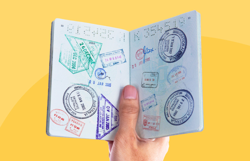 Close-up of passport stamp collection on opened passport pages, featuring colorful immigration and visa stamps from multiple countries.