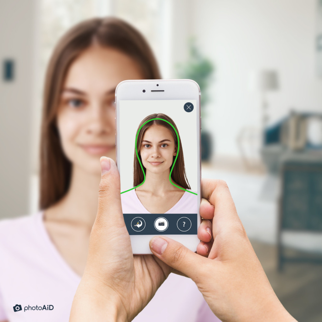 Close-up of a woman being photographed with an Android phone for a UK passport photo.