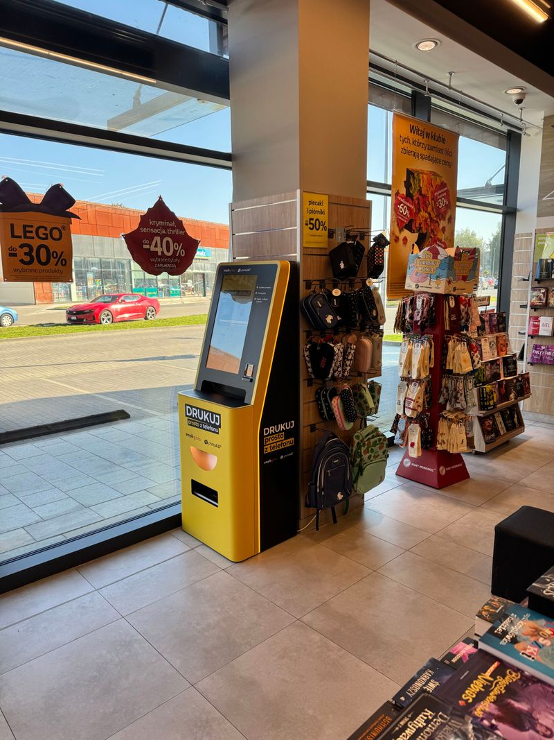 Żółto-czarny foto kiosk PhotoAiD przy wejściu do salonu Empik Babice Nowe