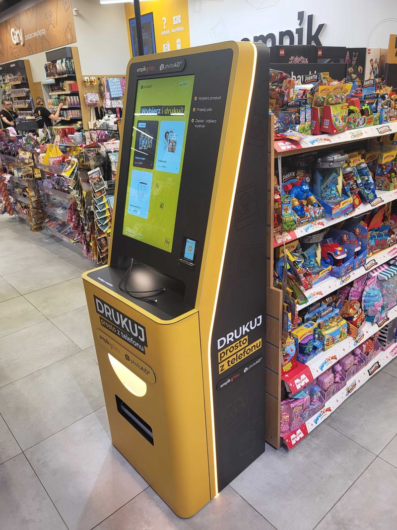 Żółto-czarny foto kiosk PhotoAiD do wydruku zdjęć i dokumentów w Empik CH M1 Kraków