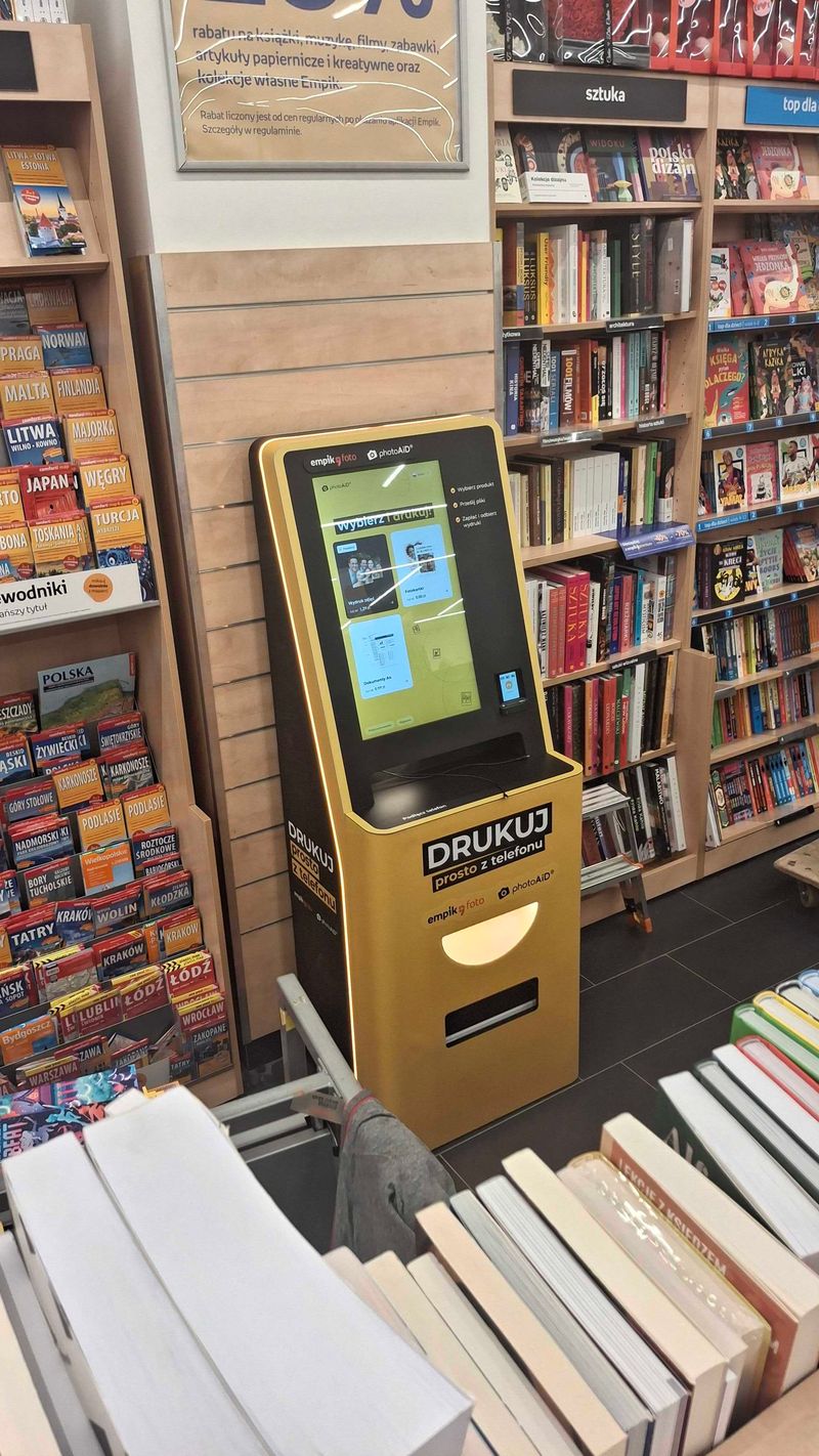 Żółto-czarny foto kiosk PhotoAiD przy dziale przewodników w Empik Galeria Olimp Lublin