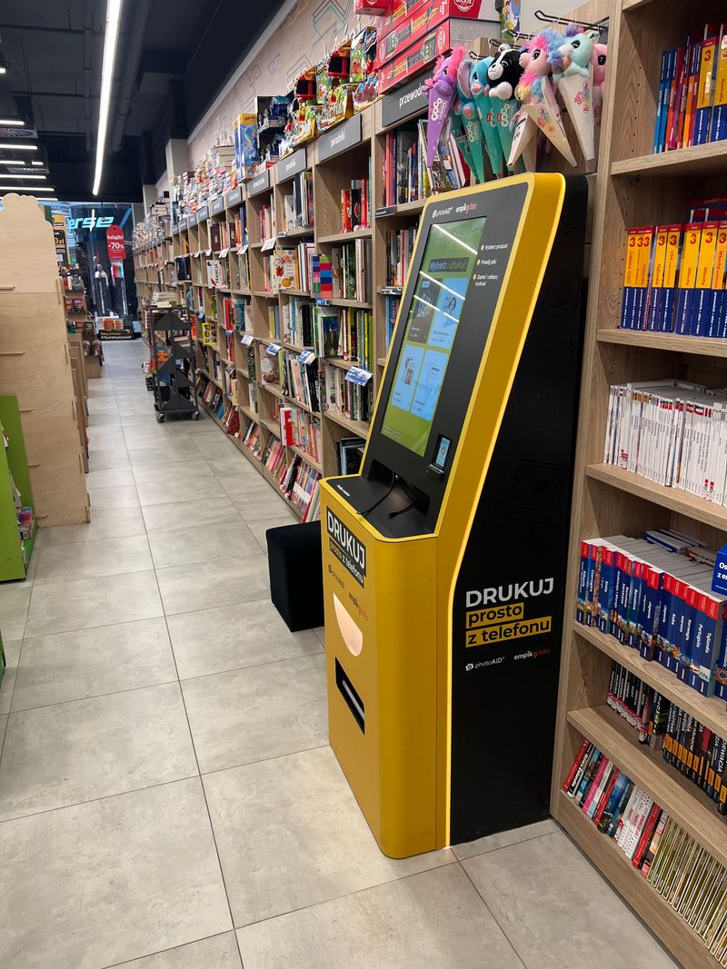 Żółto-czarny foto kiosk PhotoAiD do wydruku zdjęć i dokumentów w Empik Gdańsk Szczęśliwa