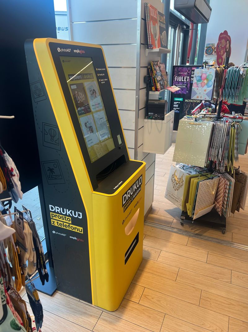 Żółto-czarny foto kiosk PhotoAiD do wydruku zdjęć i dokumentów w Empik Kraków Dekada