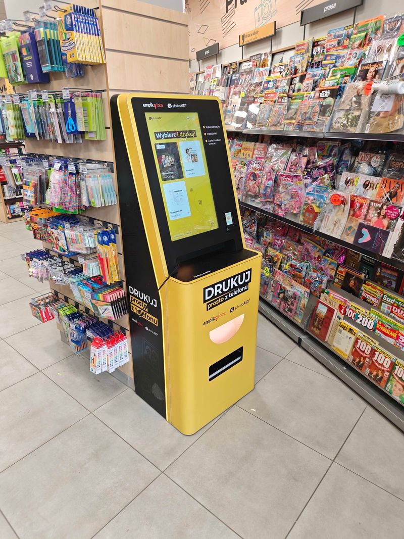 Żółto-czarny foto kiosk PhotoAiD do wywoływania zdjęć i druku A4 w Empik Łagiewnicka