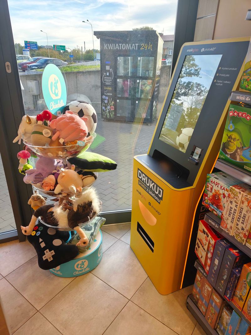 Żółto-czarny foto kiosk PhotoAiD do wywoływania zdjęć i druku A4 w Empik Zgierska w Łodzi