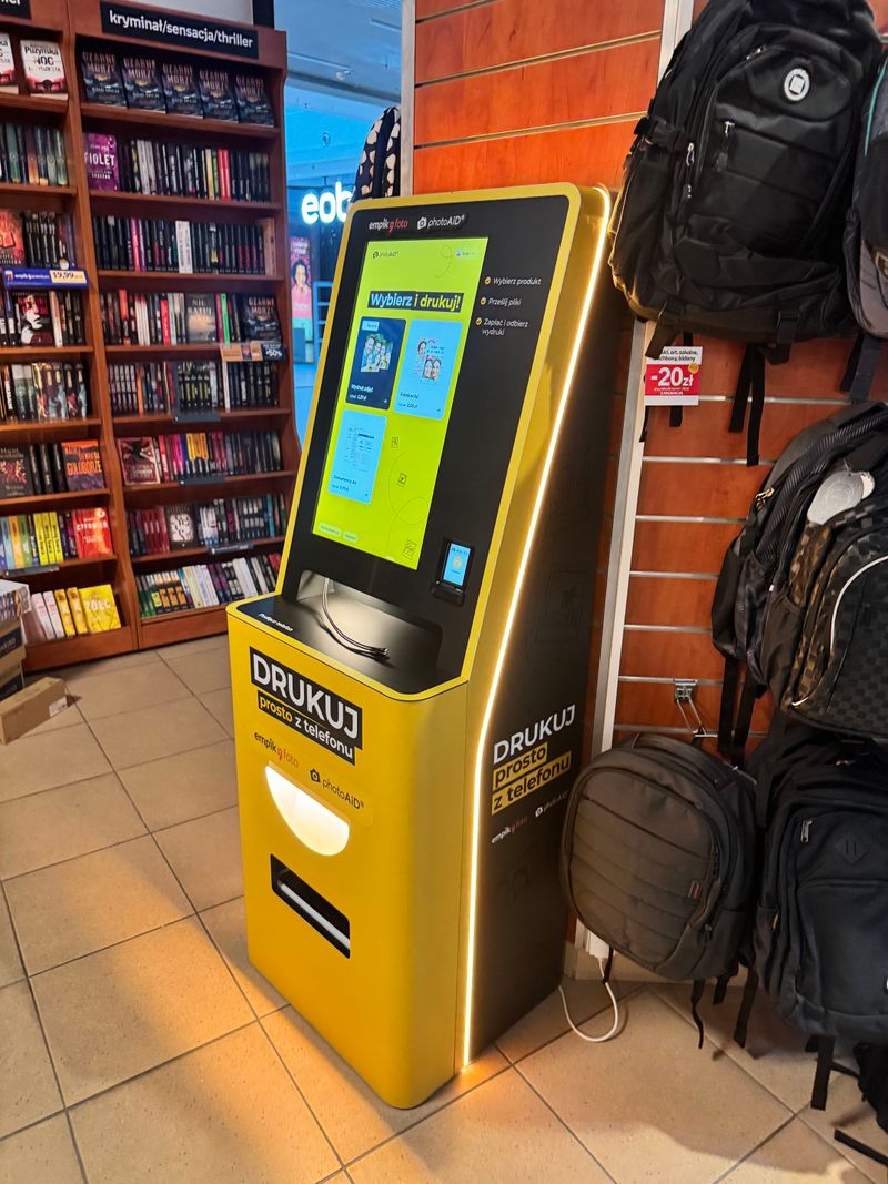 Żółto-czarny foto kiosk PhotoAiD do wydruku zdjęć i dokumentów w Empik Lublin Plaza