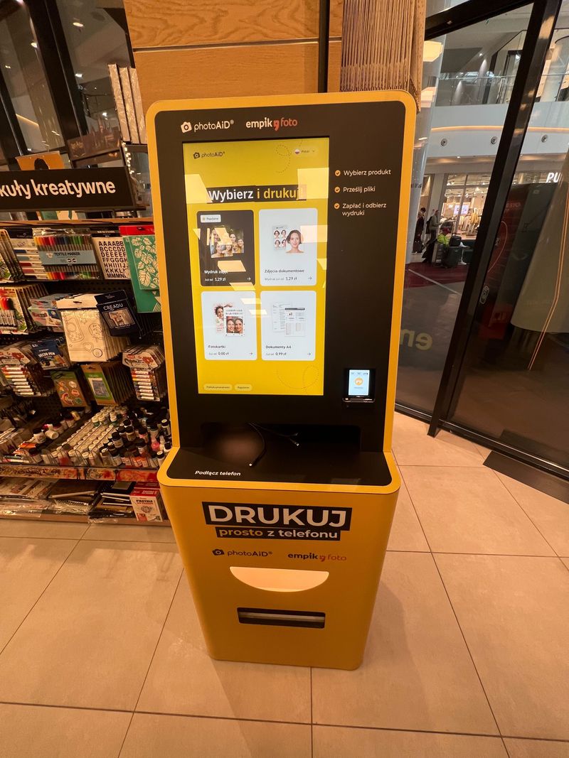 Żółto-czarny foto kiosk PhotoAiD do wydruku zdjęć i dokumentów w Empik Magnolia Park