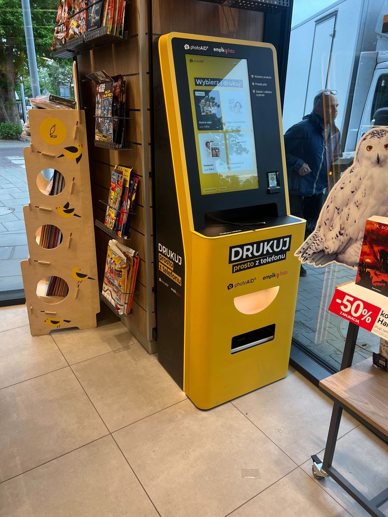 Żółto-czarny foto kiosk PhotoAiD do wydruku zdjęć i dokumentów w Empik Poznań Barańczaka