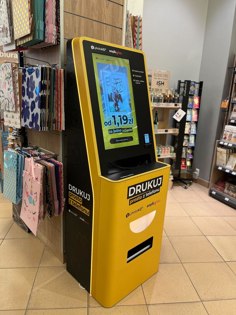 Żółto-czarny foto kiosk PhotoAiD do wydruku zdjęć i dokumentów w Empik Poznań King Cross