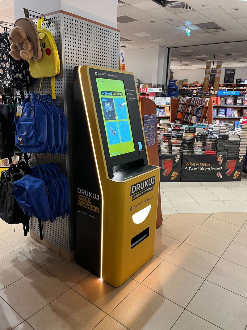 Żółto-czarny foto kiosk PhotoAiD do wydruku zdjęć i dokumentów w Empik Poznań Plaza