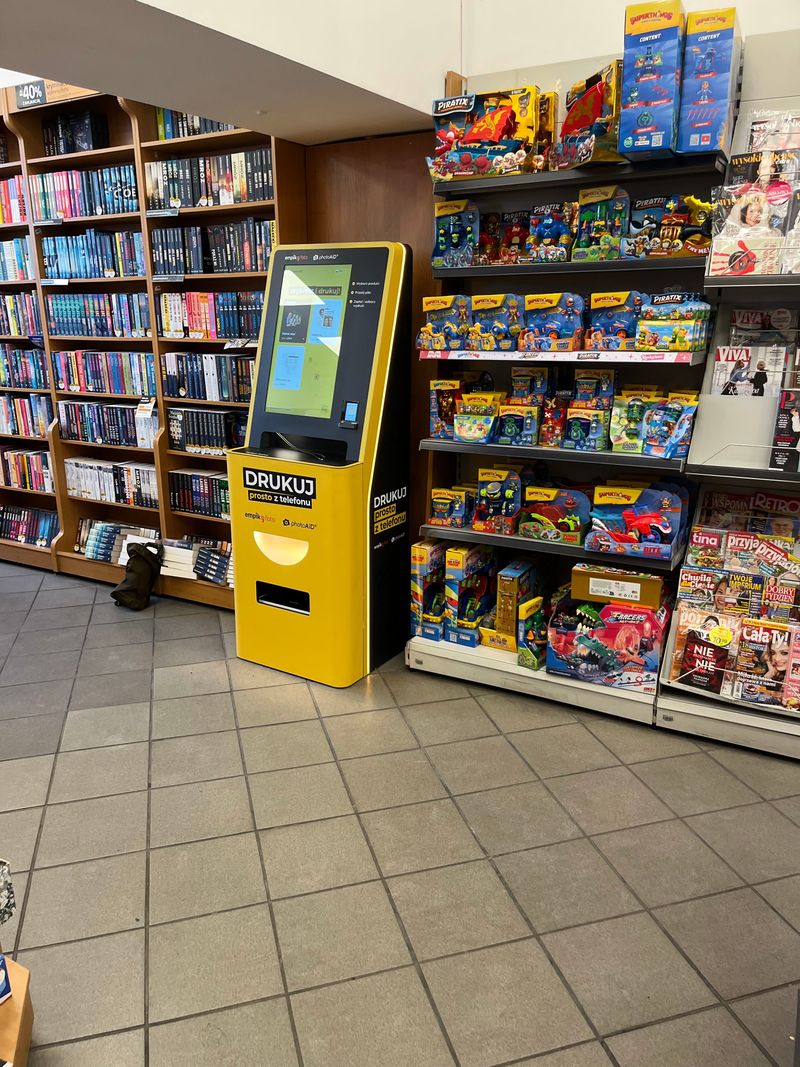 Foto kiosk PhotoAiD między regałami z książkami i zabawkami w salonie Empik w Raciborzu