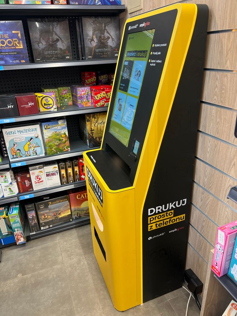 Żółto-czarny foto kiosk PhotoAiD do wydruku zdjęć i dokumentów w Empik Rental Park