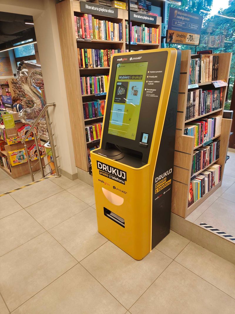 Żółto-czarny foto kiosk PhotoAiD do wydruku zdjęć prosto z telefonu w Empik Warszawa Klimczaka