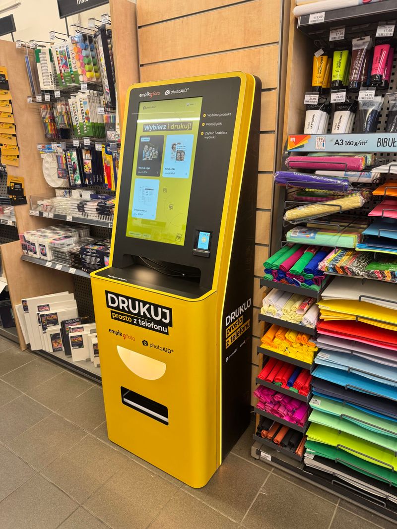 Żółto-czarny foto kiosk PhotoAiD do wydruku zdjęć i dokumentów w Empik Warszawa Mickiewicza