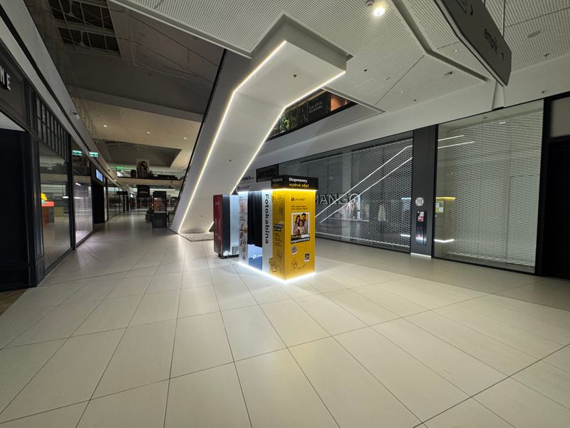 Samoobsługowy foto kiosk PhotoAiD pod ruchomymi schodami w Galerii Północnej w Warszawie